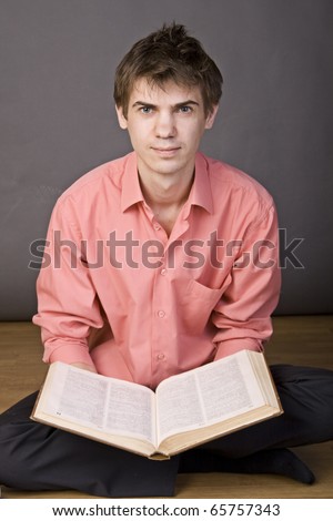 tired guy sitting on the floor with a book in her lap