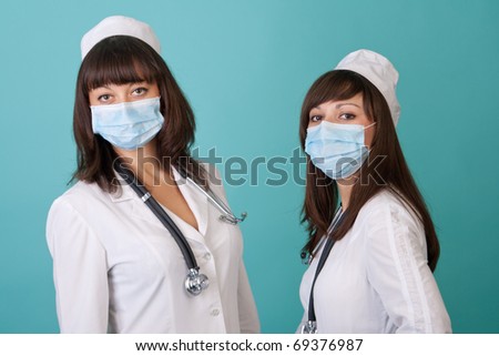 Two young woman doctor wearing a surgical mask on a blue background