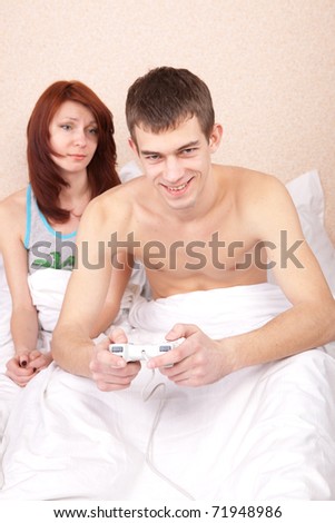 guy playing a video game in bed, she complains that she did not pay attention