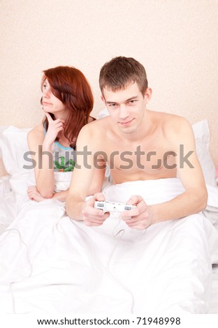guy playing a video game in bed, she complains that she did not pay attention
