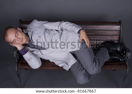 Young guy in a suit sleeping on a bench