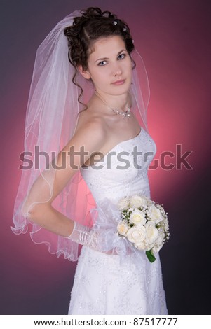 Beautiful young bride with long black hair, with a bunch of flowers. Shooting in the studio
