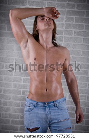 young guy with long hair, naked and wet with a muscular torso against a dark background