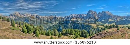 Wide panoramic photo of the Dolomites in Italy on a sunny day.