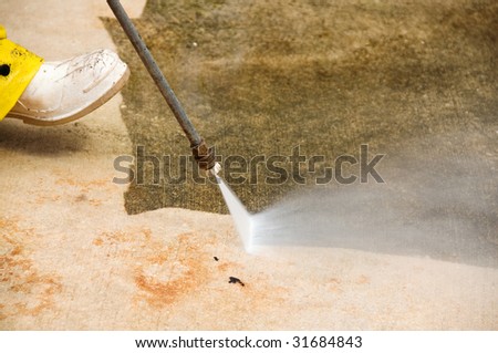 Maintenance worker cleaning old dirty driveway with a pressure cleaner