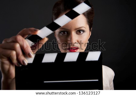 Woman with movie clap over black background