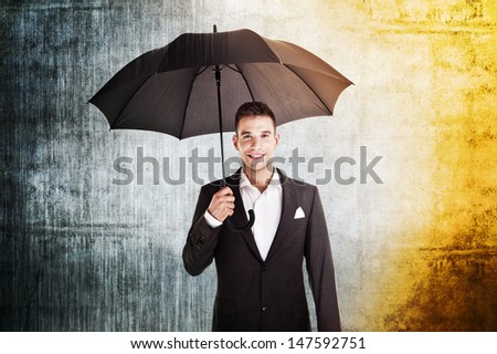 businessman in rain and sun holding umbrella