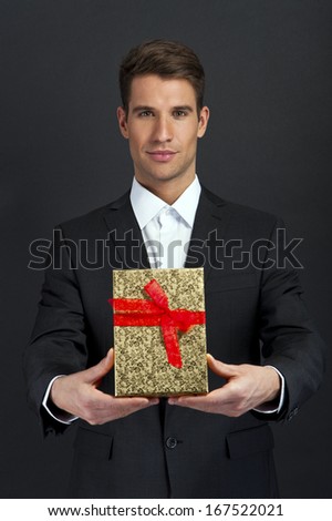 Happy young man carries  present, over dark background