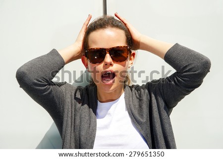 frightened woman looking at camera over light background with sunglasess