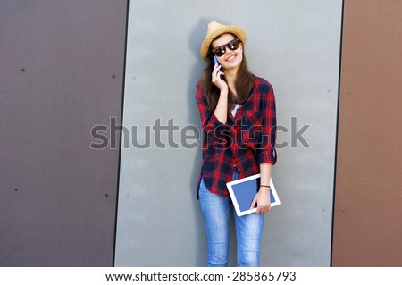 Young happy teen girl using a smart phone, tablet over wall in the background and big smile