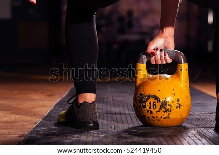 Cropped shot of female athlete exercising with kettle bell. Young sporty woman doing workout in gym.