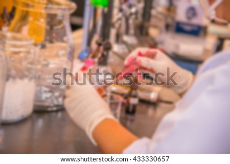 Blurred background of chemist mixing color for lipstick in laboratory/ chemistry Lab, Beaker, trowel