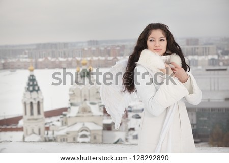 Woman with angel wings standing on the roof and looking sideways