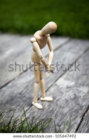 wooden mannequin standing on a wooden platform with a rope tied his hands, bowed head