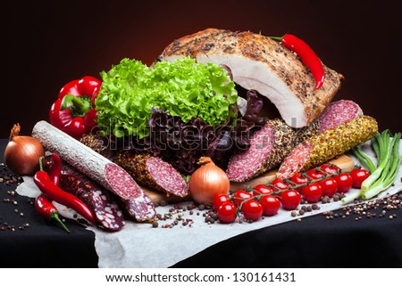 cold cuts from different kinds of meat and vegetables on a dark background