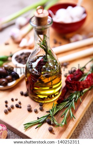 A bottle of olive oil with spices on a wooden cutting board