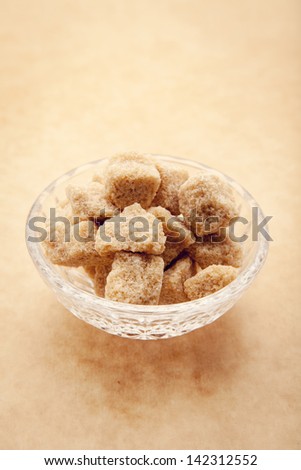 pieces of brown sugar in crystal plate on a brown background