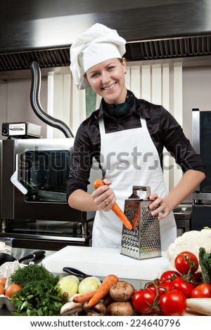 Professional female chef in a professional kitchen with carrots on a grater