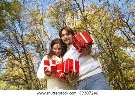 young couple gives gifts, in the autumn park