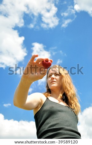 Heart in female hands against the sky