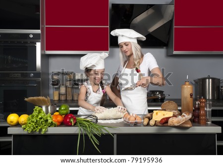mom teaches daughter to cook in the kitchen at the table with raw food, clothing cooks