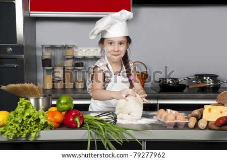 little girl chef knead the dough on the kitchen table with raw food