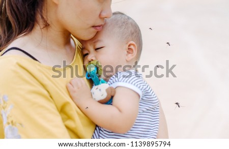 Mother holding baby boy child sleeping and Mosquito sucking blood on child skin.Allergies with mosquitoes bite and itching,protection baby from mosquito concept.