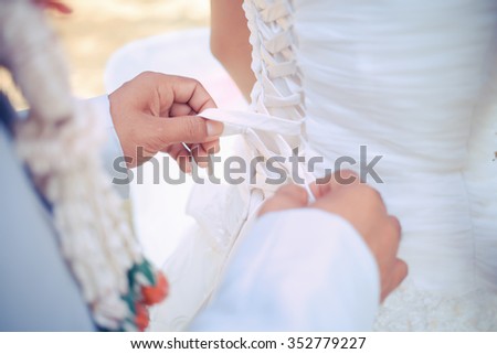 wedding dresses laces, Closeup toned photo of beautiful bride tying up her wedding dress