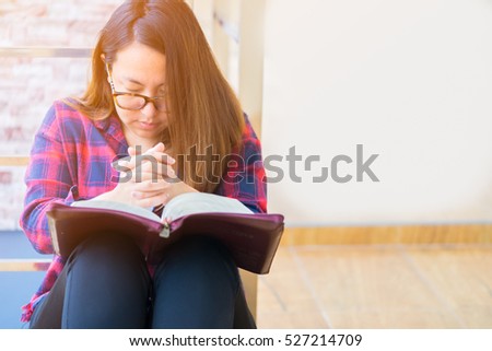 woman praying on holy bible in the morning.teenager woman hand with Bible praying,Hands folded in prayer on a Holy Bible in church concept for faith, spirituality and religion