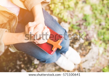 man praying on holy bible in the morning.teenager man hand with Bible praying,Hands folded in prayer on a Holy Bible in the garden concept for faith, spirituality and religion