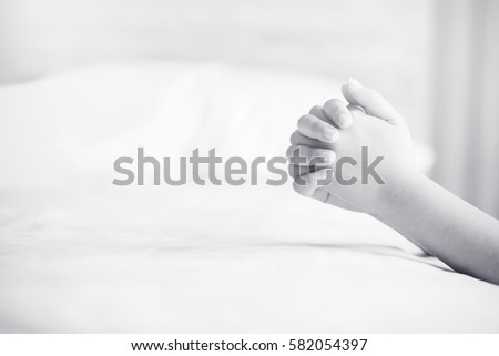 woman praying on the bed in the morning.teenager woman hand praying,Hands folded in prayer on the bed in the morning concept for faith, spirituality and religion.Black and white.