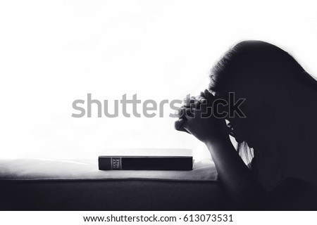 Silhouette woman praying on holy bible in the morning.teenager woman hand with Bible praying,Hands folded in prayer on a Holy Bible in church concept for faith, spirituality and religion