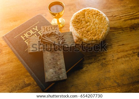 Holy communion on wooden table on church.Taking Communion.Cup of glass with red wine, bread and Holy Bible and Cross on wooden table.The Feast of Corpus Christi Concept.