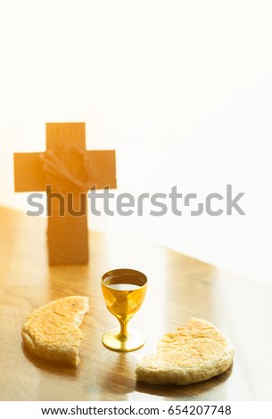 Holy communion on wooden table on church.Taking Communion.Cup of glass with red wine, bread and Holy Bible and Cross on wooden table.The Feast of Corpus Christi Concept.