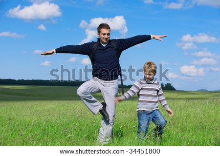 The man and the boy against the nature stand on one foot trying to keep balance