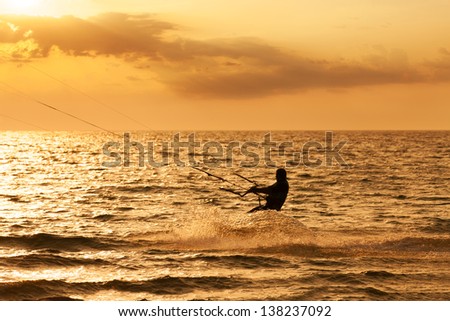 Kite surfer jumping from the water at sunset ocean
