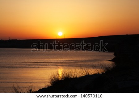 Sunset in the sea bay with grass silhouette