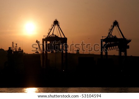 Sea port at sunrise, cranes silhouettes