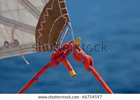 red rope, knot and piece of sail isolated on blue on sailing boat