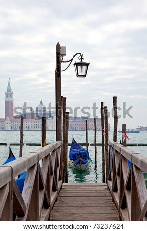 Gondola at the end of the bridge with blue cover in Venice at the pier