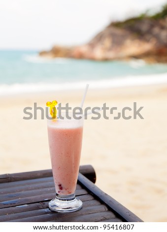 Milk cocktail in glass with ice and straw on ocean beach background