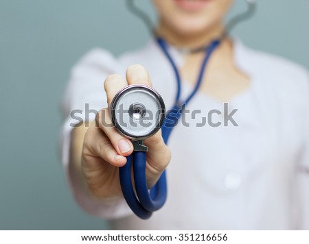 Medical doctor woman   on a blue background holding a stethoscope focus on the stethoscope