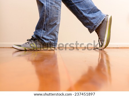 Man in blue jean walking on wooden floor