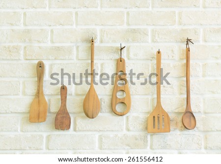 Wooden kitchen utensils on white brick wall