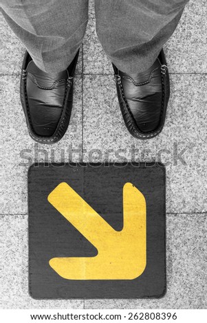 Business man standing on road with direction arrow