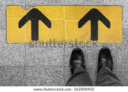 Business man standing on road with direction arrow