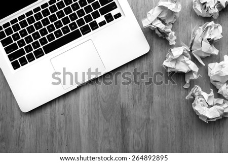 Computer notebook and crumpled paper on wooden table