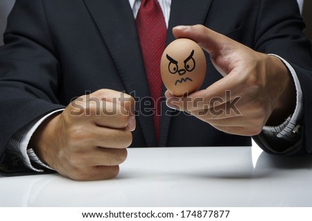 Businessman holding Angry Egg character and other hand fist hit the table
