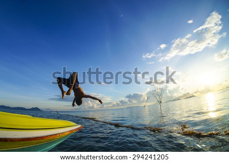 SIBUAN ISLAND, SABAH, MALAYSIA - JUNE 6 : Unidentified Sea Bajau\'s boy back-flip from the boat during sunrise June 6th, 2014 in Sibuan Island, Sabah Malaysia