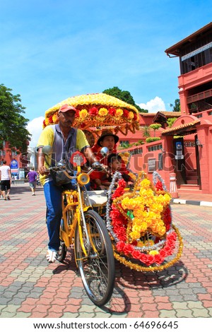 MALACCA, MALAYSIA - NOVEMBER 6: Tourist on the famous hi-tech decorative trishaw on November 6, 2010 in Malacca. The trishaw ride is a major attraction for visitors to see the city of Malacca.